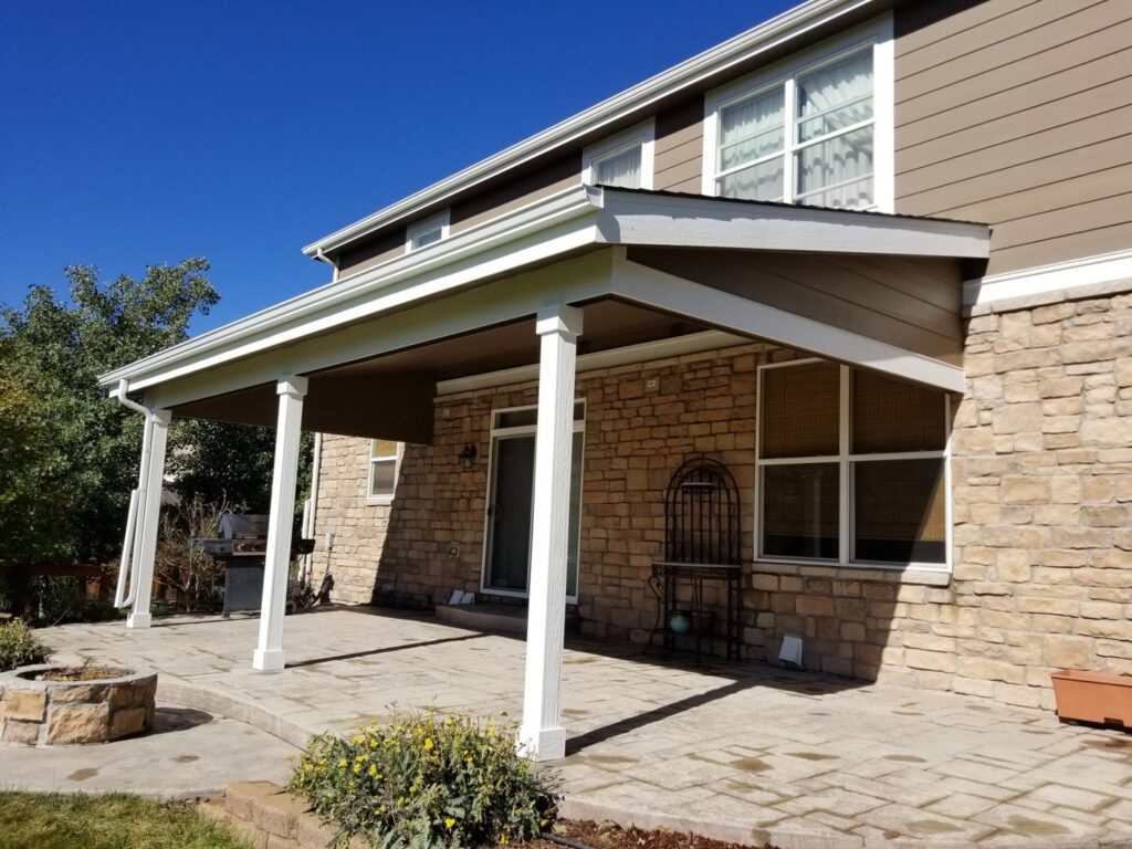 A newly installed patio cover attached to a stone-sided house by Lnk Deck & Remodels, LLC in Aurora, CO.