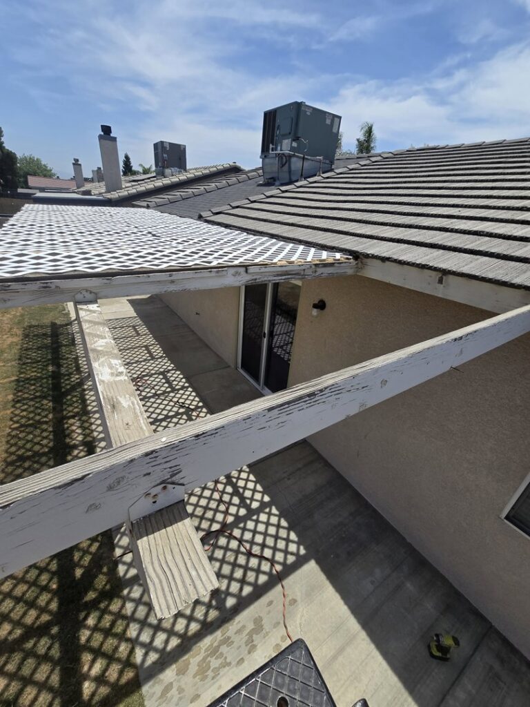 An old patio cover with peeling paint and lattice, indicating a need for repair by Bakoboy Enterprise Inc in Bakersfield, CA.