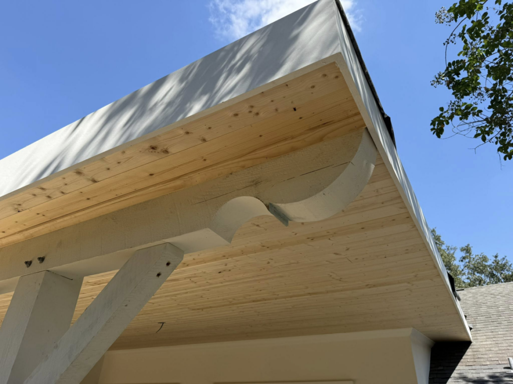 Close-up of the detailed wooden ceiling and decorative corbels of a patio cover by Acadian Carpentry LLC in Lafayette, LA.