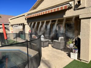 A high-quality mist system installed on a patio next to a pool with a safety fence and awning by Mr. Mister in Surprise, AZ