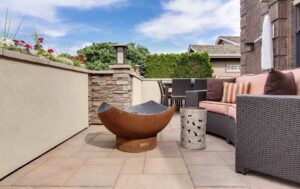 A contemporary patio with a unique metal fire pit and outdoor seating by St. Charles Deck in St. Charles, MO