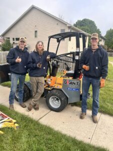 Three Patriot Tree Service crew members posing with a mini-loader on a job site in Sioux Falls, SD