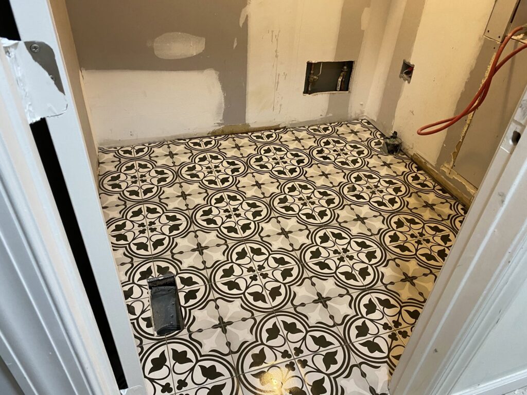 A newly installed patterned floor tile in a utility room by Goubar Tile And More in Raleigh, NC.