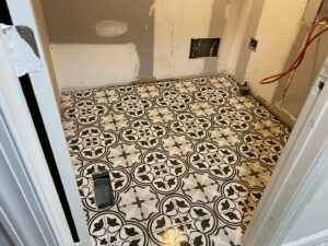 A newly installed patterned floor tile in a utility room by Goubar Tile And More in Raleigh, NC.