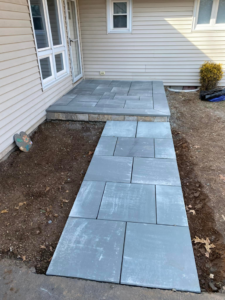 A new paver patio and walkway installed next to a house by Tomori's masonry llc in Cheshire, CT