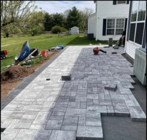 A paver patio under construction with pavers laid out and tools on site by Mincho Contractor LLC in Jersey City, NJ