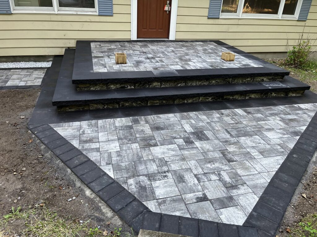 A newly installed paver patio and steps leading to a house entrance by Mincho Contractor LLC in Jersey City, NJ