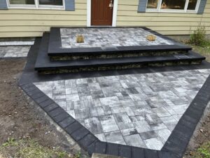 A newly installed paver patio and steps leading to a house entrance by Mincho Contractor LLC in Jersey City, NJ