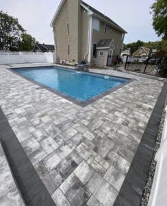 A newly installed paver pool deck surrounding a swimming pool by Mincho Contractor LLC in Jersey City, NJ