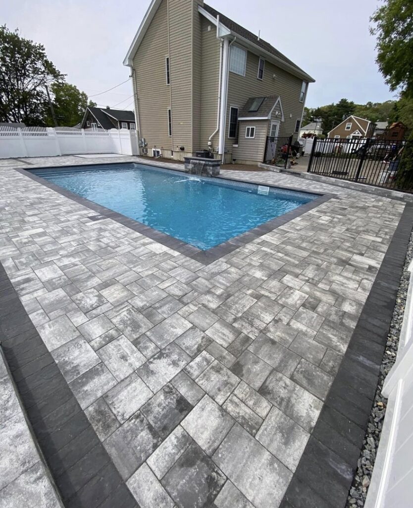 A newly installed paver pool deck surrounding a swimming pool by Mincho Contractor LLC in Jersey City, NJ