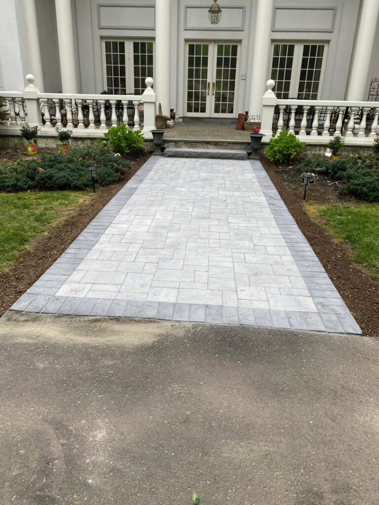 A newly installed paver walkway leading to a house entrance by Leo Brothers Contracting in Danbury, CT.