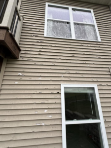 Exterior siding with severe peeling paint and a broken window, ready for repair by Larson Exteriors in Sunset Hills, MO.