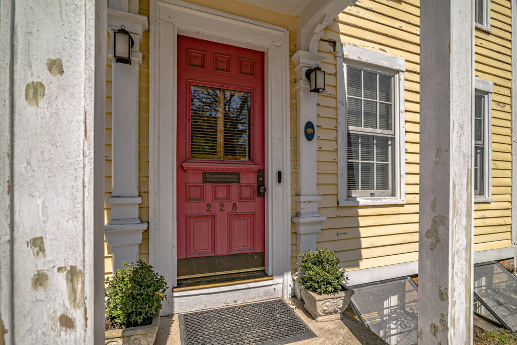 A red front door with peeling paint on the trim, showing a need for handyman services from GO Painting in New Haven, CT