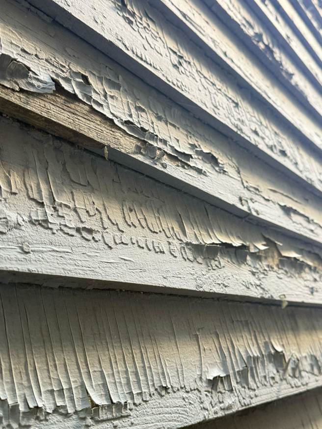 Close-up of peeling paint on house siding, indicating a need for exterior repair by Isac's General Services LLC in Henrico, VA