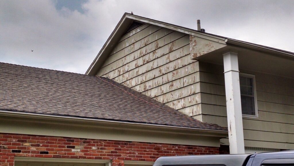 Close-up of peeling paint on house siding, indicating a need for repair by E.L. Construction in Kansas City, MO.