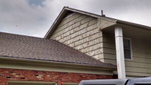Close-up of peeling paint on house siding, indicating a need for repair by E.L. Construction in Kansas City, MO.