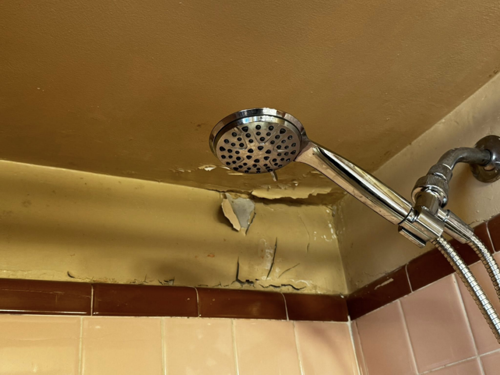 Peeling paint and drywall damage on a shower wall, requiring repair from S & H Painting and Drywall LLC in Montgomery, AL.