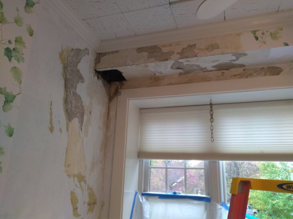A wall with peeling wallpaper and damaged plaster, indicating a renovation or repair project by N. Bennecoff Drywall & Plaster in Lancaster, PA.