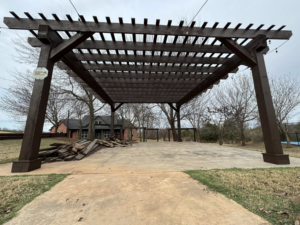 A wooden pergola with construction debris nearby, indicating work by Oklahoma Painting & Construction in Oklahoma City, OK.