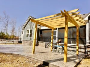 Wooden pergola under construction on a stamped concrete patio by BOS HOME Exterior Services in Virginia Beach, VA