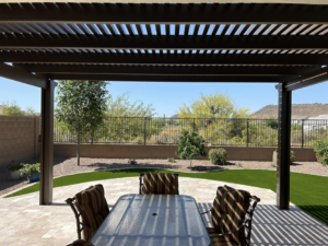 A completed brown pergola providing shade over a patio dining area by Az Sun Covers in Glendale, AZ.