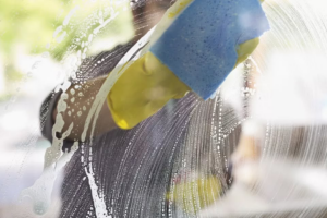 A person cleaning a window with a sponge, demonstrating window cleaning services by Gerald Jones Company in Durham, NC.