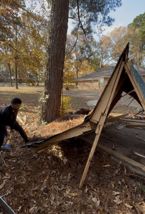 A person clearing debris from a collapsed shed, demonstrating junk removal services by Nash's Cargo Company LLC in Shreveport, LA.