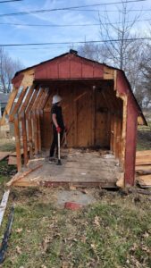 A person in a hard hat demolishing a shed, part of a junk removal service by T&G Dumping in Lorain, OH.