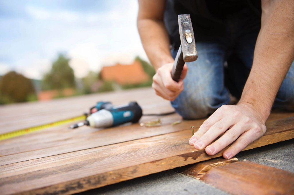 A person hammering a nail into a wooden board, representing handyman services by Gibson's Southwest Maintenance in Phoenix, AZ.