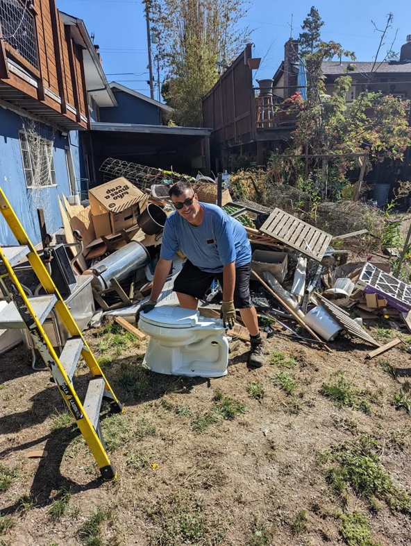 A worker holding a toilet in a yard full of debris during a junk removal job by Glenn's Junk & Landscape Hauling in Renton, WA.