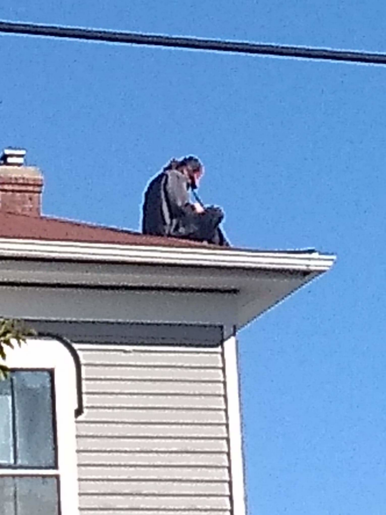 A person inspecting the roof edge and gutter of a house at Superior Roof Support in Milano, TX.