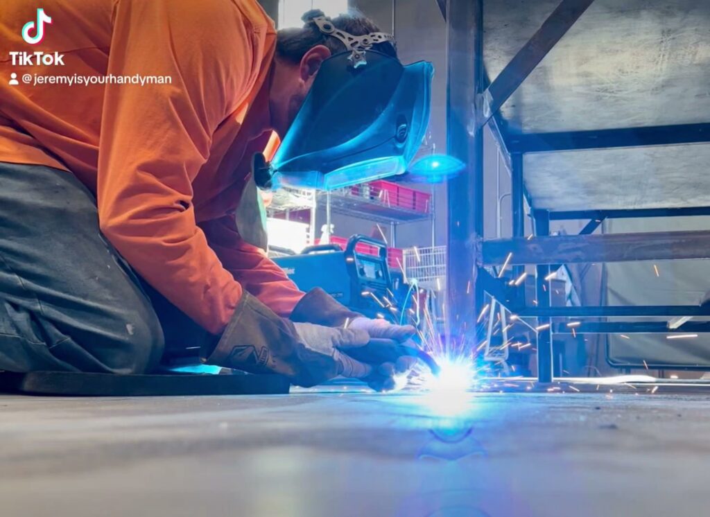 A person kneeling and performing welding work with bright sparks, demonstrating services by Jeremy's Welding & Handyman in West Jordan, UT.