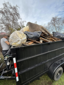 A person loading construction debris and insulation into a trailer for Junk Away & Cleaning in Sacramento, CA.