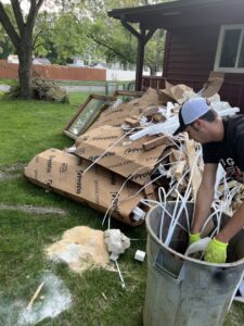 A person loading construction debris into a trash can for removal by Cash For Scrap Vehicles / Junk Removal in Minneapolis, MN.