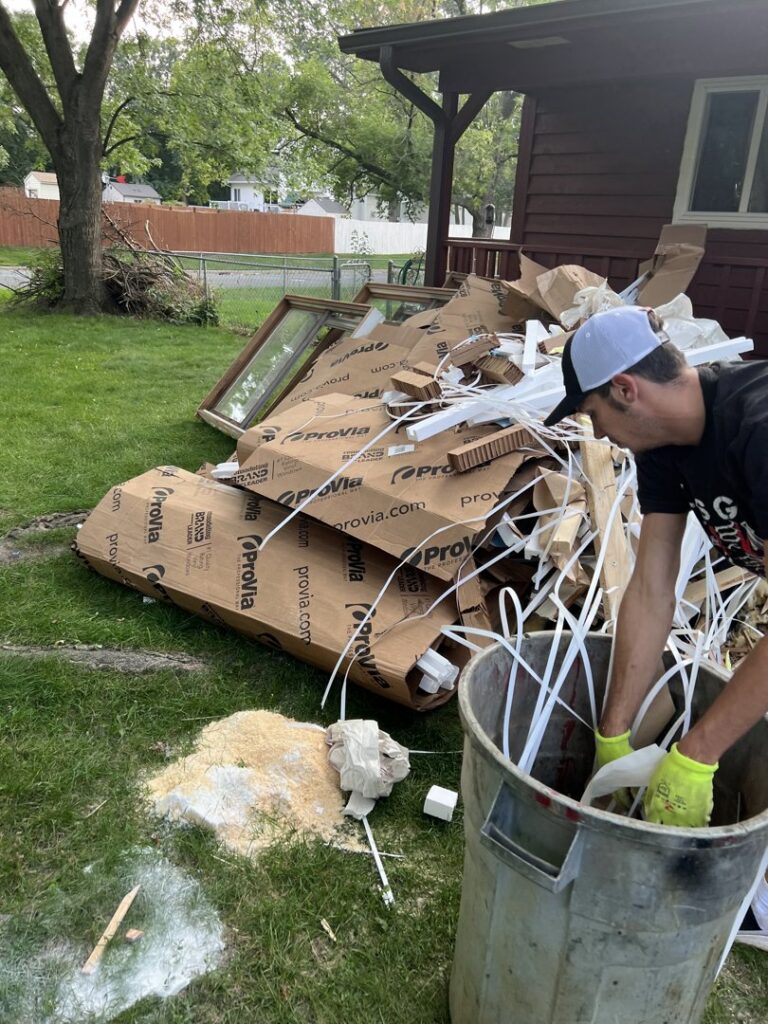 A person loading construction debris into a trash can for removal by Cash For Scrap Vehicles / Junk Removal in Minneapolis, MN.