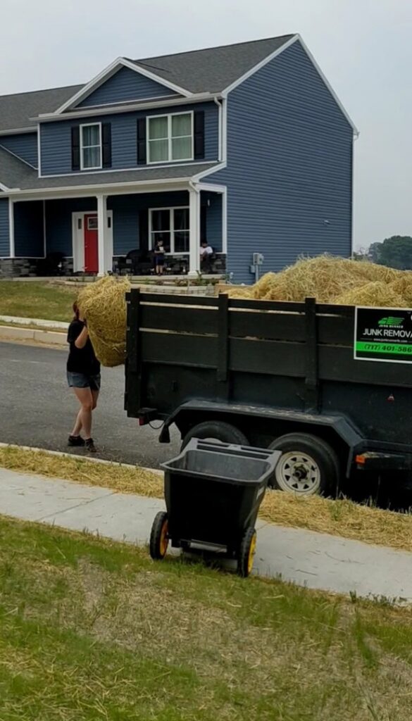 A person loading hay or straw into a junk removal trailer for Junk Runner, LLC in East Berlin, PA.