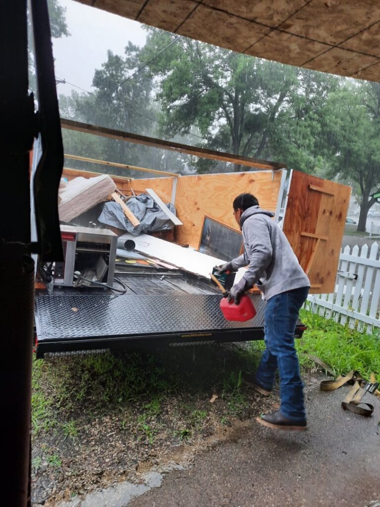 A person loading various items into a junk removal trailer, demonstrating the service provided by Sunshine junk removal LLC in Lake City, MN.