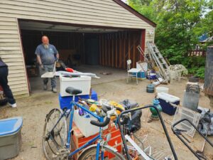 A person loading various junk items like a bicycle, ladder, and buckets into a trailer for CC JUNK Removal in Corpus Christi, TX.