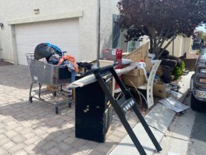 A person wearing gloves loads a bag of trash into a large blue dumpster, demonstrating junk removal by Mike's Dumper in Las Vegas, NV.