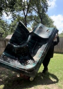 A Grawe Junk & Demo team member moving a large, broken hot tub on a dolly across a grassy lawn for removal in Arlington, TX.