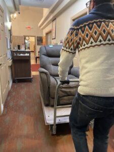 A Tidy Toss Las Vegas, NV team member moving a recliner on a hand truck down a hallway for removal.