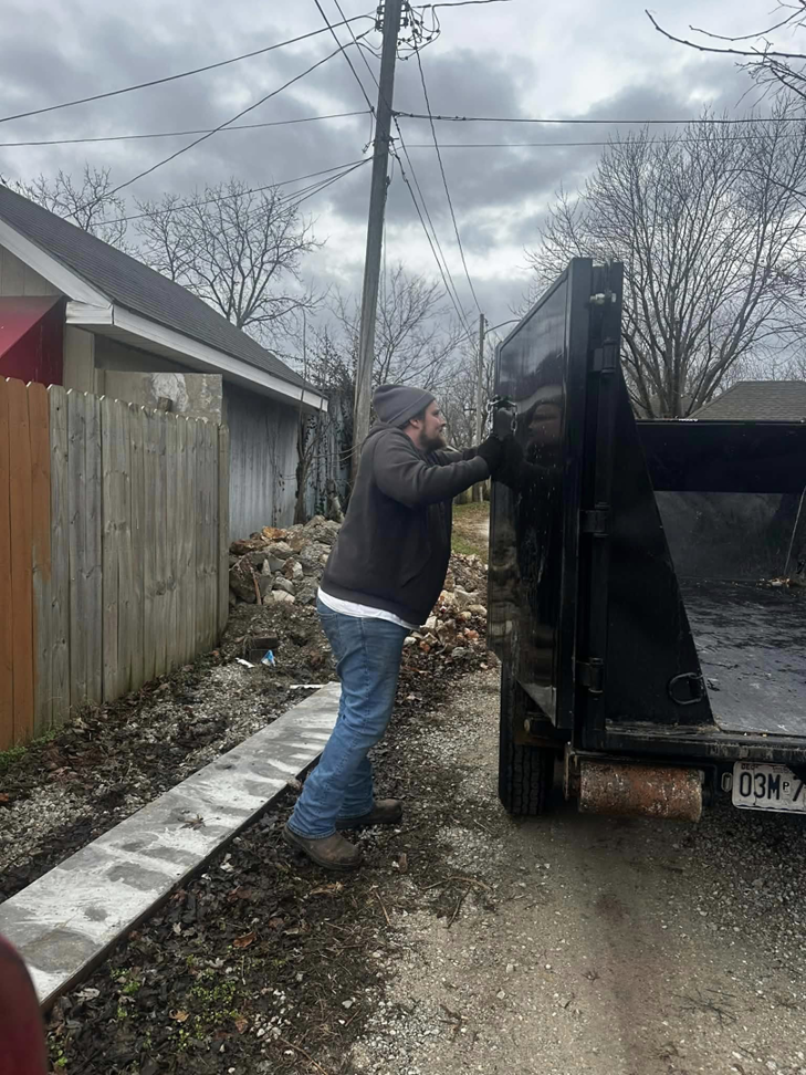 A person opening the back gate of a junk removal trailer for Tornado Alley Junk Removal & Trash in Springfield, MO.
