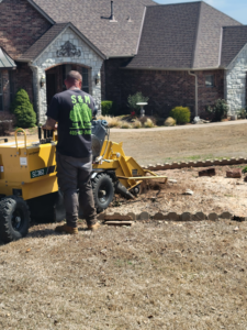 A person from S & M Tree Service, LLC operating a stump grinder to remove a tree stump in Edmond, OK.