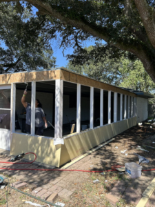 A person painting the frame of a new screened porch addition by Nugent Construction LLC in River Edge, NJ.