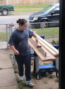 A person painting or staining wood boards on a workbench for Do-N-All Handyman Service in Wichita, KS.