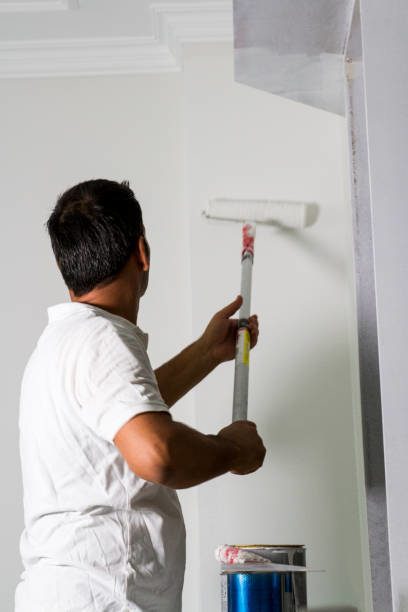 A person painting a residential wall with a roller, a service by A 'n' G Residential in Amsterdam, NY.