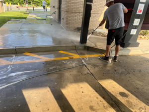 A person pressure washing a concrete walkway and drive-thru area for Selk Solutions in Crossville, TN.