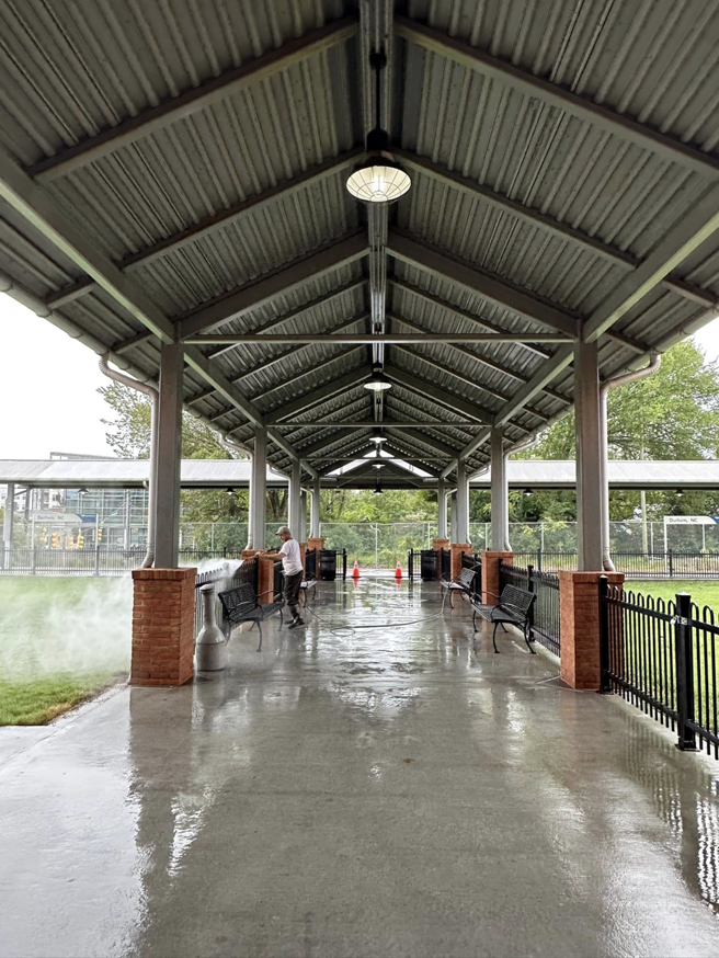 A person pressure washing a concrete walkway under a covered structure, performed by S & S Pressure Washing and Painting Co. in Burlington, NC.