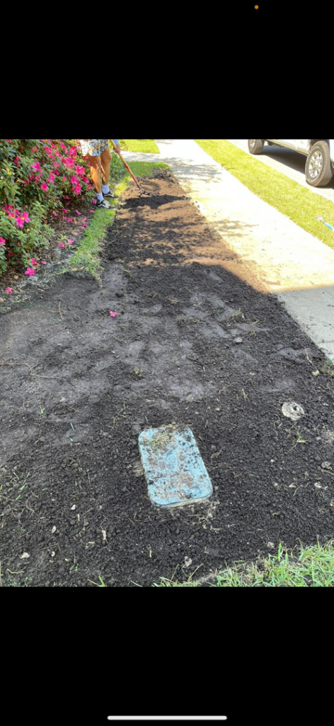 A person raking soil for a landscaping project, demonstrating handyman services by A and T Services LLC in North Charleston, SC.