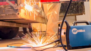 A person performing welding work with sparks flying, using a Miller machine, by Jeremy's Welding & Handyman in West Jordan, UT.
